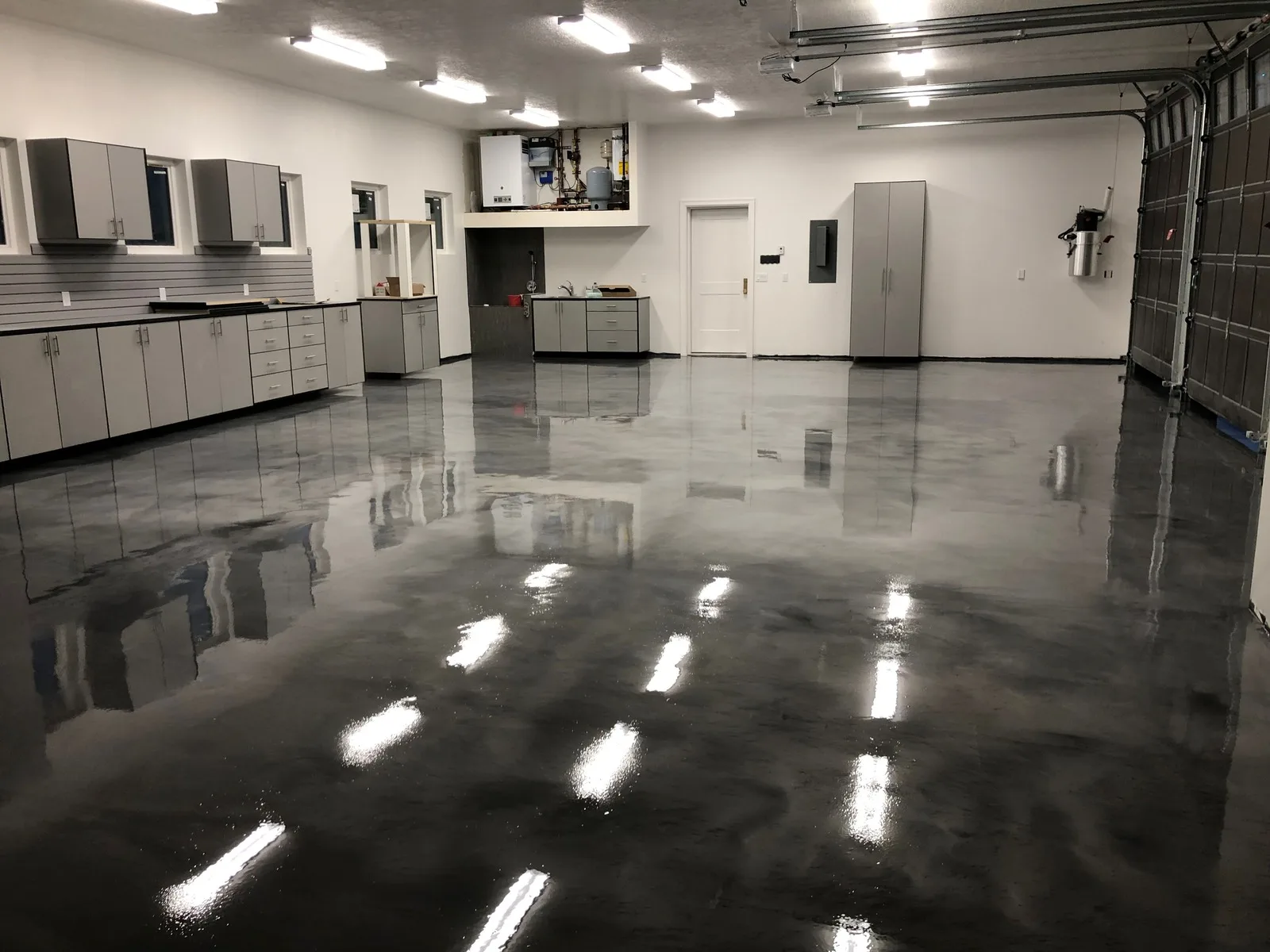 Gloss gray coated garage floor with cabinets and a bright ceiling light