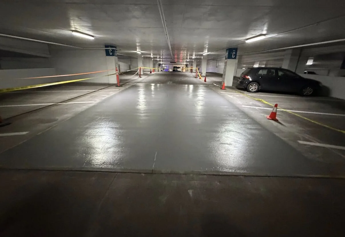 Gray floor coating curing in a parking garage between cones and caution tape