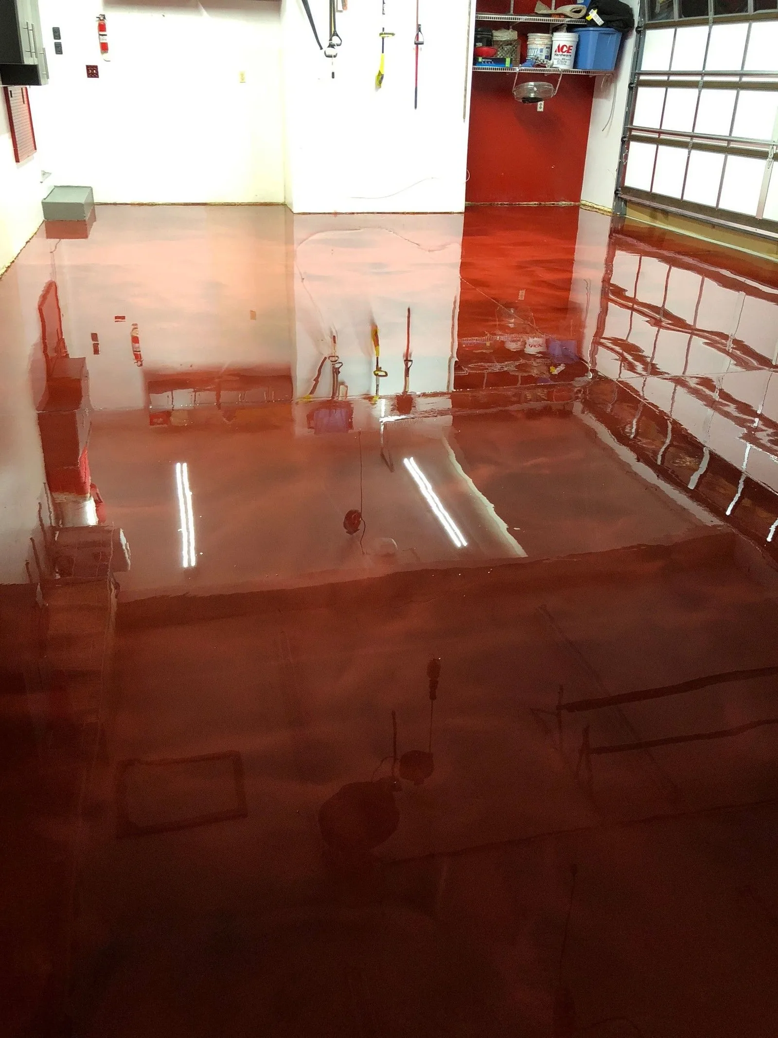 Red metallic epoxy garage floor with the garage door open to daylight